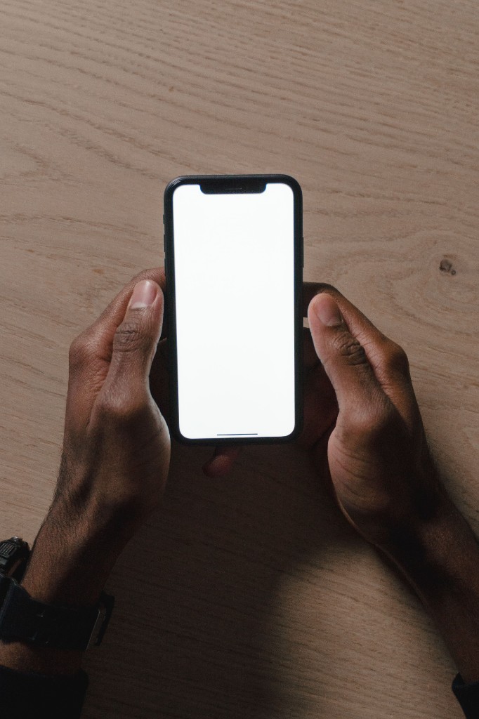 Hands holding a smartphone over a wooden table